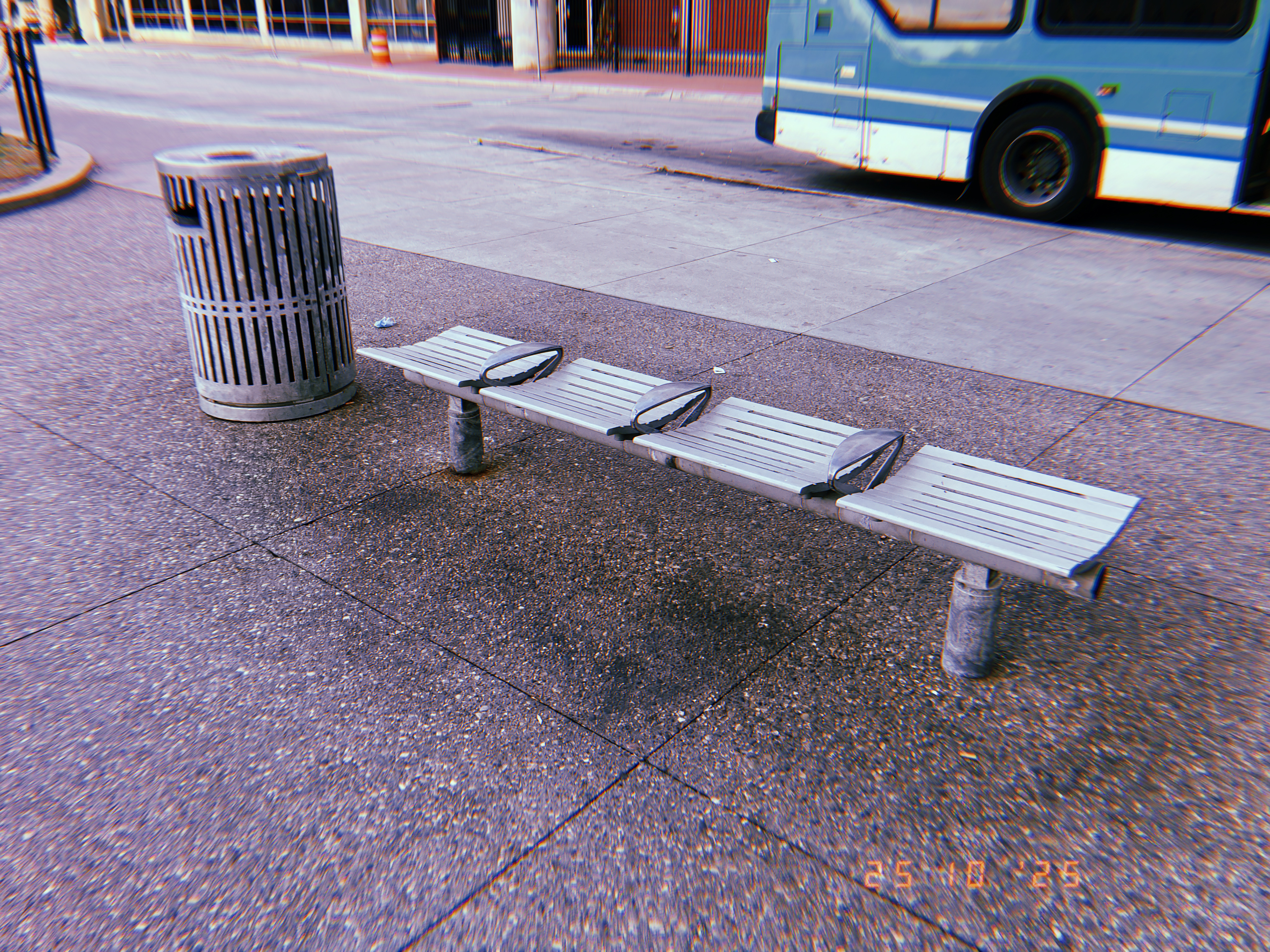 Bus stop bench and trash can on a downtown Detroit sidewalk as a bus pulls up